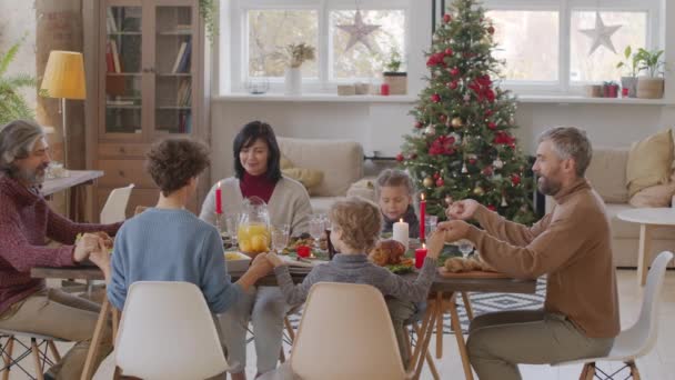 가족이 크리스마스 기도를 하면서 식탁에 모습이 사진에 찍혔다 — 비디오