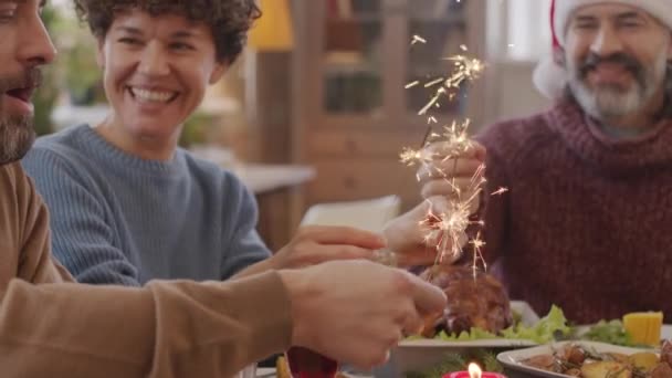 Close up shot of happy young woman and bearded men sitting at Christmas table together and holding sparklers — Stock Footage Close Shot Happy Young Woman Bearded Men Sitting Christmas Table Stock Video