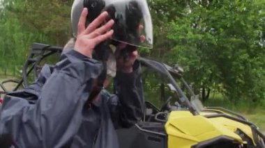 Sakallı, orta yaşlı bir adam bisikletine biniyor ve açık havada kask takıyor.