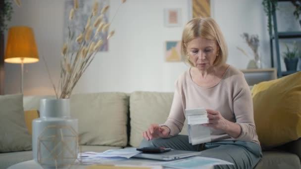 Orta Yaşlı Beyaz Kadının Kağıt Işleriyle Uğraşırken Hesap Makinesi Yazma — Stok video