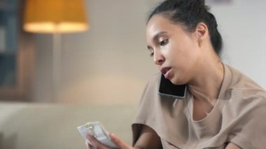 Ciddi genç bir kadının mali danışmanla telefon görüşmesi yapması gelir sayılarını kontrol etmesi ve dizüstü bilgisayarın faturalarını elinde tutması.