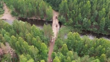 Kırmızı dört tekerli bisikletle ormanda köprüde uçan ve duran tanınmayan insanların görüntüsü.