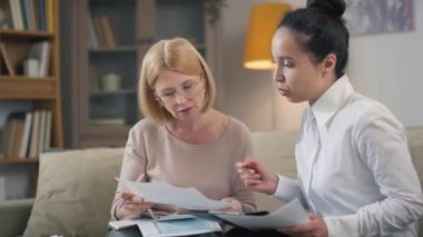 Orta ölçekli, beyaz gömlekli, orta yaşlı kadınların finansal okur yazarlık ve planlama temellerini anlatan genç, melez bir finans danışmanı.