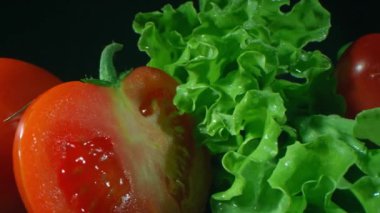 Kırmızı tatlı biberlerin ve sulu domateslerin makro görüntülerini stüdyo yüzeyinde kıtır marul ve salatalıklar arasında tarıyorum.