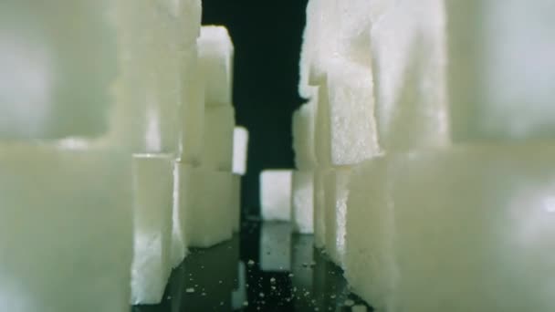 放大独立的白糖立方体在工作室黑暗表面形成塔楼的宏观画面 — 图库视频影像
