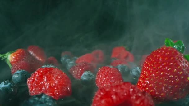 混合イチゴ ラズベリーとブルーベリーのパンのマクロの飼料は 新たに選んだと暗いスタジオの背景に煙の中で横に洗浄 — ストック動画