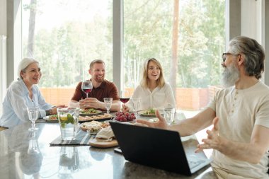 Gülümseyen yaşlı baba ve yetişkin oğul arka bahçedeki gezintiden sonra kulübeye girerken konuşuyorlar.