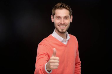 Siyah arka planda kameraya göz kırpan neşeli sakallı genç adamın portresi.