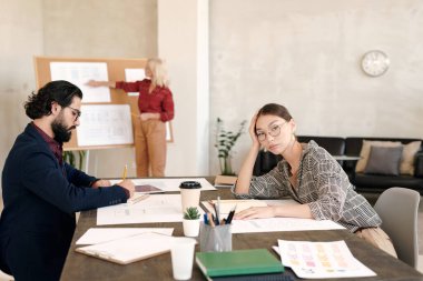 Kültürler arası resmi giyimli genç meslektaşlar kameranın önünde oturmuş yetişkin sarışın iş kadınının sunumunu hazırlıyorlar.