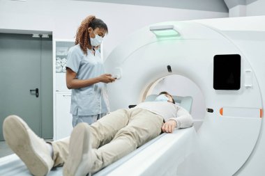 Hasta odasında hemşirelerle sonuçları tartışırken röntgen görüntüsüne bakan laboratuvar önlüklü ciddi bir olgun doktor.