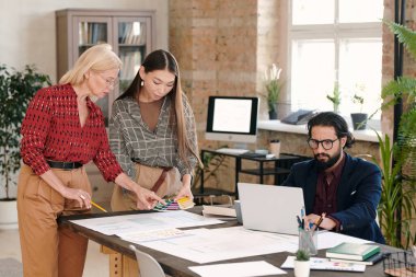 Yeni mobil uygulama için renk seçen iki yaratıcı kadın tasarımcı dizüstü bilgisayarlı genç meslektaşları çevrimiçi veri ararken