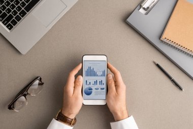 Genç modern ekonomist ya da muhasebecinin finansal verileri ekranda analiz ederken akıllı telefonu tutmasının düz çizimi