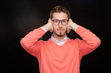 Turuncu kazaklı genç adam saklambaç oynarken ya da korkarken elleriyle gözlerini kapatıyor.