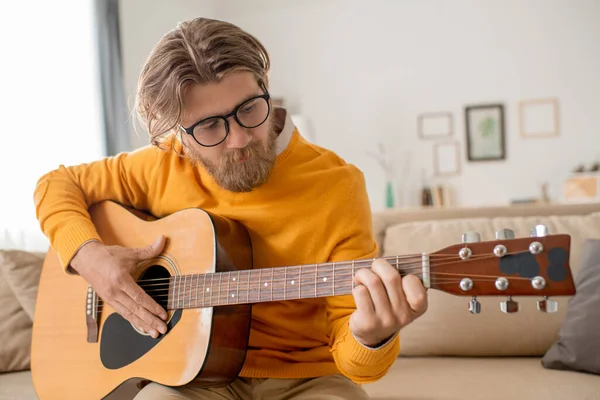 Jovem Contemporâneo Jeans Jumper Amarelo Sentado Sofá Puxando Cordas Guitarra — Fotografia de Stock