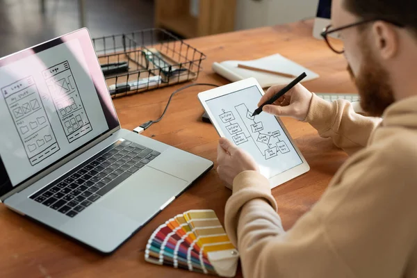 年轻的男性自由软件开发人员在平板电脑屏幕上手握触笔 同时绘制新智能手机模型的方案草图 — 图库照片