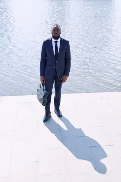 Fiatal Afrikai Üzletember Fekete Bőrtáskával Kezében Miközben Járdán Áll Kamera — Stock Fotó