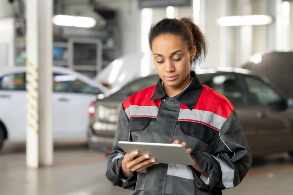 現代の自動車サービスの若い混合レースの女性技術者は クライアントのオンライン質問を読みながら デジタルタブレットの表示に触れる — ストック写真