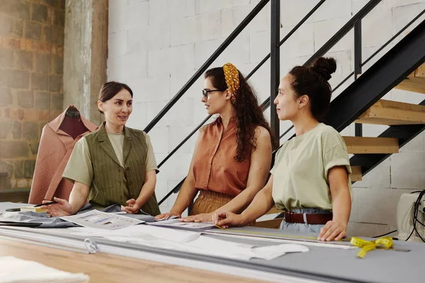 Duas Jovens Estagiárias Exibindo Novos Esboços Itens Moda Consultando Com — Fotografia de Stock