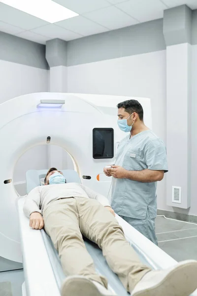 头戴外科口罩的多愁善感的医生和护士分析病人在病房睡觉时的X光图像 — 图库照片