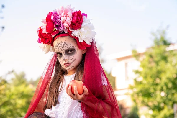 年轻的闷闷不乐的姑娘站在镜头前 脸上涂满了油彩 头上插着美丽的花朵 手里拿着成熟的苹果 — 图库照片