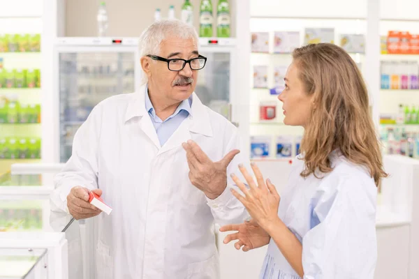 Senior Male Pharmacist Holding New Medicaments While Consulting His Young — Stock Photo, Image