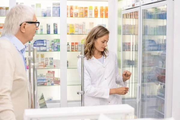 Bastante Joven Asistente Farmacia Mirando Los Medicamentos Exhibición Mientras Consulta — Foto de Stock