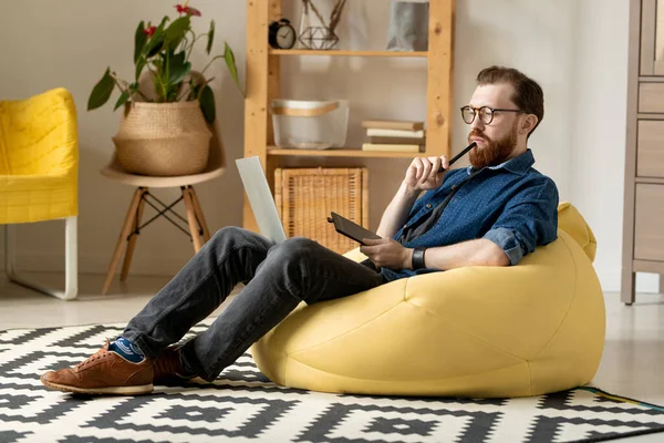 Young Pensive Male Freelance Designer Eyeglasses Casualwear Sitting Comfortable Armchair — Stock Photo, Image