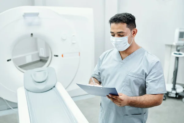 Close-up of unrecognizable nurse in surgical gloves filling patients card in hospital