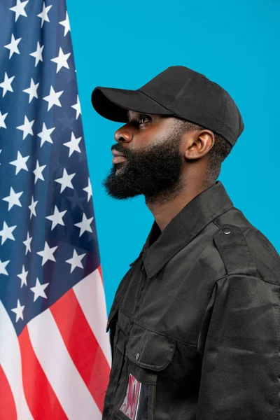 身穿黑色制服 头戴黑色帽子 与星条旗隔离站立的年轻的 留着胡子的非裔美国男性安全侧视图 — 图库照片