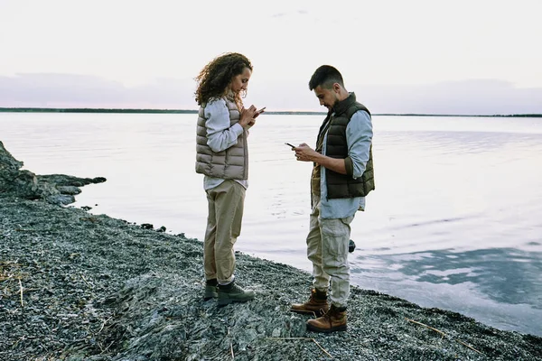 Concentré Jeune Couple Debout Sur Plage Galets Utilisant Des Gadgets — Photo