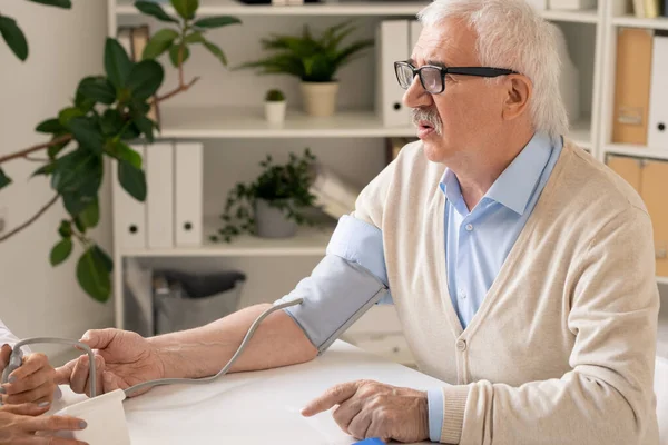老年人坐在病床旁测量血压的过程中 向医生求医 — 图库照片