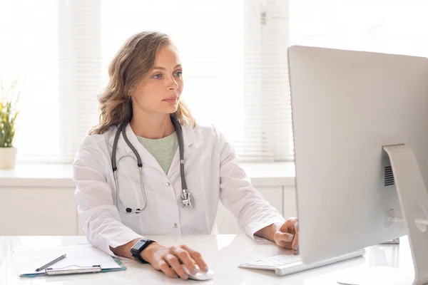 Ung Allvarlig Läkare Whitecoat Tittar Igenom Uppgifter Sina Patienter Medan — Stockfoto