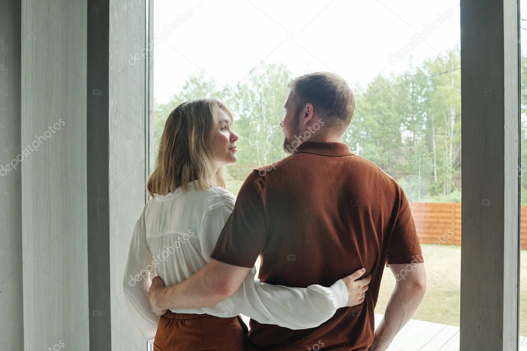 Rear view of young couple embracing each other while dreaming of future into new house