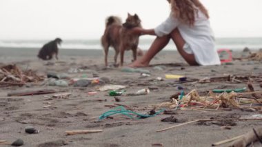 Uzun kıvırcık saçlı, uzun saçlı, terk edilmiş kumsalda köpek besleyen, tanınmayan yalnız bir kadının yüz görüntüsü yok.