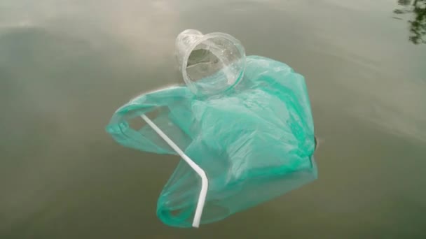 汚れた水に浮かぶビニール袋やストロー カップなどのゴミのトップビューショット海洋ごみを傷つける — ストック動画
