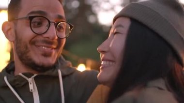 Romantik, çok ırklı çiftlerin konuşmalarını ve gülümsemelerini yaz akşamı ışıklarla süslenmiş güzel mekanlara bakarak yakın durun.