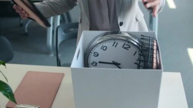 Tanımlanamayan bir kadın ofis masasında duruyor ve birkaç eşyasını kutusundan çıkartarak iş gününe başlıyor.