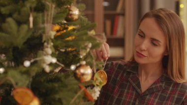 Kafkasyalı güzel bir kadının Noel ağacını kuru portakallarla süslediği yakın plan.