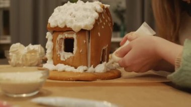 Noel masasında bolca kremayla süslenmiş el yapımı zencefilli kurabiye evi.