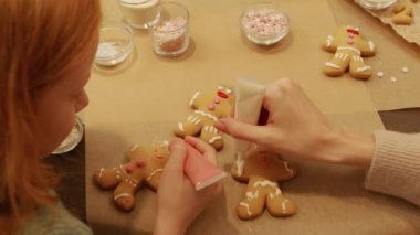 Küçük kızıl saçlı bir kız ve annesinin Noel masasında fırında zencefilli kurabiye yaparken en iyi görüntüsü.