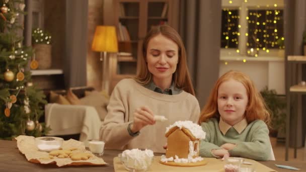 소녀와 그녀의 집에서 진저브레드 하우스를 꾸미고 크리스마스 트리와 거실에 웃으며 — 비디오