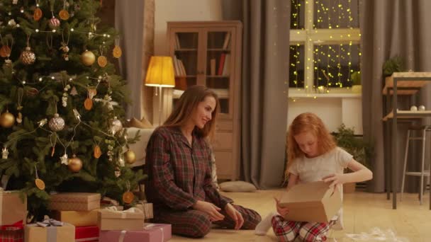 체크무늬 잠옷을 엄마와 크리스마스 상자에서 토끼를 꺼내는 — 비디오
