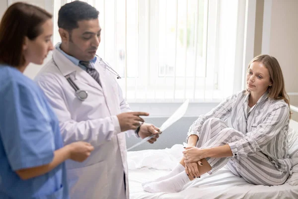 Mujer Joven Enferma Sentada Cama Mirando Médico Confiado Apuntando Papel —  Fotos de Stock