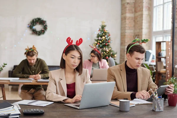 年轻的跨文化同事们穿着时髦的便服 戴着圣诞头巾 成排坐在笔记本电脑前 结成网络 — 图库照片