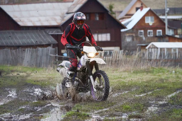 Motorcoss Rider Wyścigi Wsi Przed Rzędem Drewnianych Domów — Zdjęcie stockowe