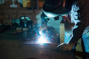 Tanımlanamayan bir adam atölyesinde koruyucu kask takıyor.