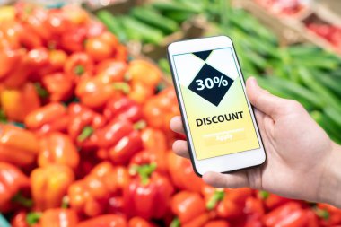 Ekranında indirimli uygulama ve arka planda meyveler olan tanınmayan akıllı telefonun yatay yakın çekim görüntüsü