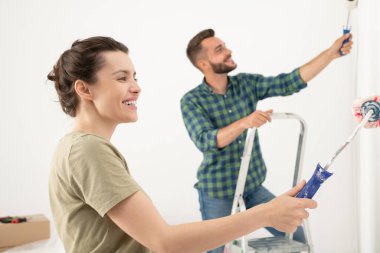 Gülümseyen, yakışıklı bir adam, duvarları boyayarak ızdırap çekerken aynı zamanda odayı karımla dekore ediyorum.