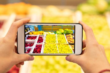 Ekranında indirimli uygulama ve arka planda meyveler olan tanınmayan akıllı telefonun yatay yakın çekim görüntüsü