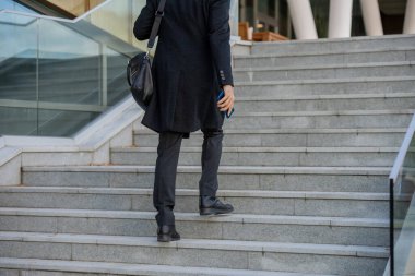 İş merkezine giderken üst kata çıkan çantalı ve akıllı telefonlu çağdaş zarif iş adamının arka planı